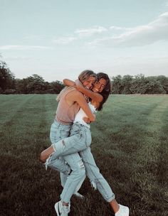 two women hugging each other in the middle of a field