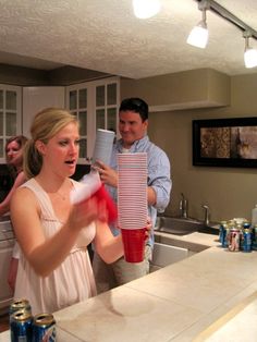 a man and woman standing in a kitchen next to a counter with cans on it