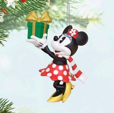 a mickey mouse ornament hanging from a christmas tree with a present in it