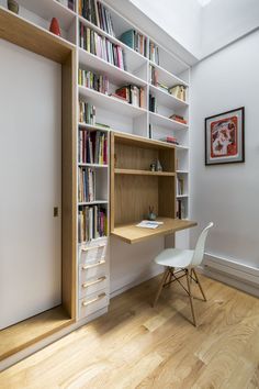 a white chair sitting in front of a desk with bookshelves on it and a book case behind it