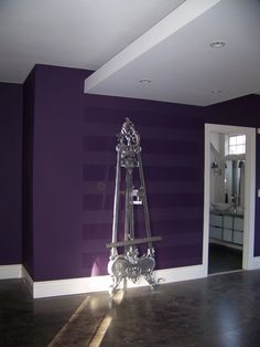 a room with purple walls and a silver clock on the floor in front of it