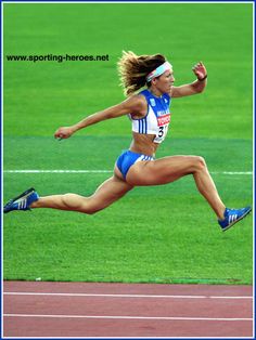 a woman running on a track in a blue and white outfit with her hair blowing in the wind