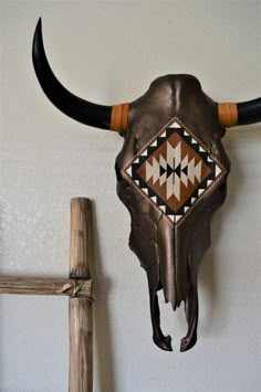 a cow's skull hanging on the wall next to a wooden stick and cross