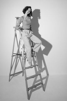 a woman sitting on top of a wooden ladder