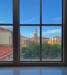 an open window with a view of a building and trees in the foreground, looking out