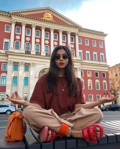 a woman sitting on top of a bench in front of a building