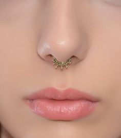 a woman's nose has a gold nose ring on it, and is wearing pink lipstick