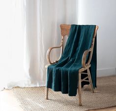 a chair with a blanket draped over it in front of a window and rug on the floor