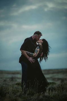 a man and woman kissing in the middle of a field