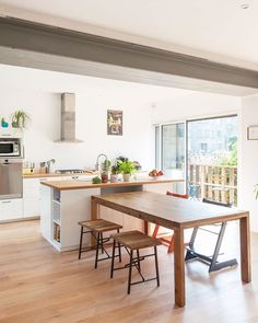 an open kitchen and dining area with wood floors, white walls, and stainless steel appliances