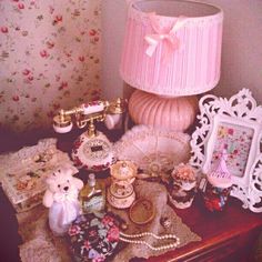 a table topped with lots of assorted items and a pink lamp on top of it