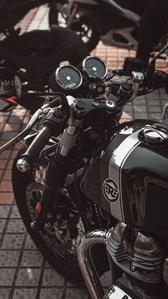 two motorcycles parked next to each other on a brick floored area in front of a building