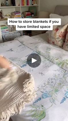 a bed that has been made with white sheets and pillows on top of it, in front of a bookcase full of books