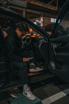 a man sitting in the driver's seat of a car looking at his cell phone