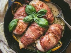 some meat and vegetables in a skillet on a table with a cloth next to it