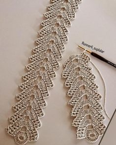 the crocheted lace is being worked on with a marker and thread, next to it