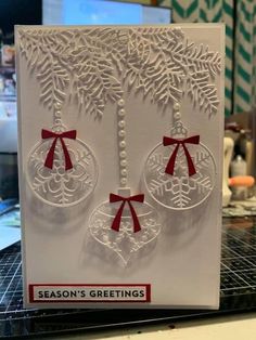 a white card with red bows and ornaments hanging from it's sides on a table