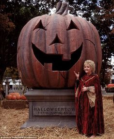 a woman standing next to a carved pumpkin