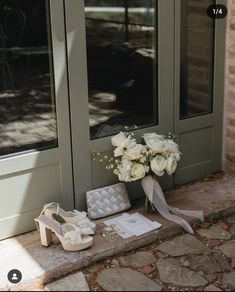 a bouquet of white flowers sitting on top of a stone floor next to a pair of shoes