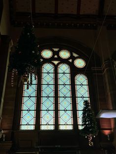 a large stained glass window in the middle of a building with christmas decorations hanging from it's ceiling