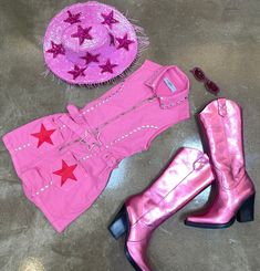 a pink cowboy outfit and boots are on the floor next to a purple cowgirl hat