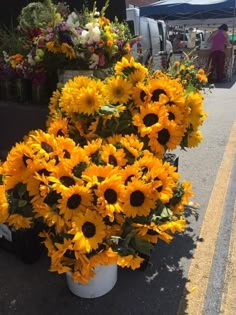 sunflowers and other flowers are on display at an outdoor market