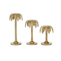 three brass palm trees on pedestals against a white background