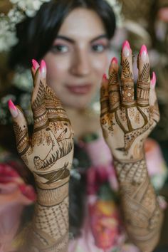 a woman holding her hands up to show the hendi designs on her hand and face