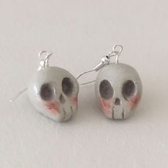 pair of skull earrings with red and white paint on them