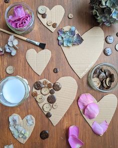 paper hearts are arranged on a table with buttons, flowers and other crafting supplies