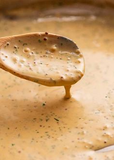 a wooden spoon filled with cheese sauce