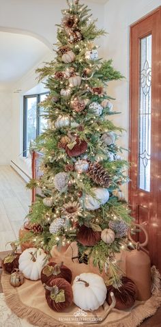 a christmas tree decorated with pine cones and white pumpkins