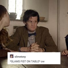 two people sitting at a table talking to each other and one person wearing a bow tie