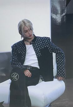 a man sitting on top of a white chair next to a black and white wall