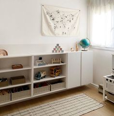 a room with a rug, bookshelf and other items on the floor in front of a window