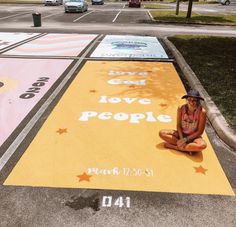 a woman is sitting on the ground in front of a painted street with words and stars