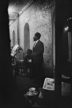 a man in a suit standing next to a wall and looking at something on the table