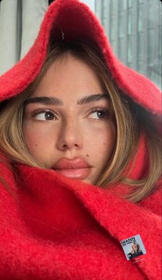 a young woman is wrapped in a red blanket and looking at the camera with an intense look on her face