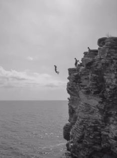 a person jumping off the edge of a cliff into the ocean