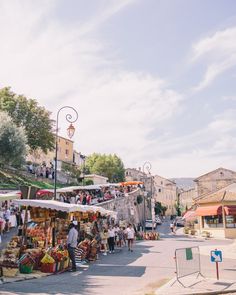 people are shopping at an outdoor market on a sunny day