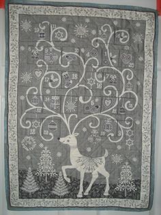 a quilted wall hanging with a deer and snowflakes on the tree in it