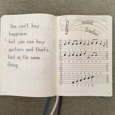 an open notebook with music notes and writing on the pages, in which you can't buy happiness but you can buy guitars and that's kind of the same thing