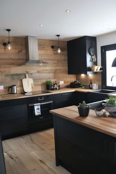 a kitchen with wooden floors and black cabinets, an island in the middle has potted plants on it