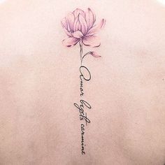 the back of a woman's neck with a pink flower and words on it