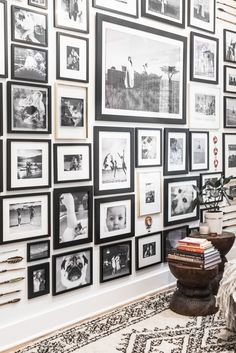 a living room filled with lots of framed pictures on the wall next to a coffee table