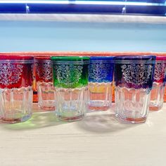 five different colored glasses lined up on a table