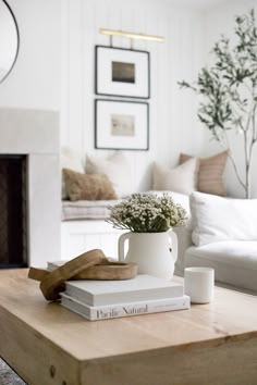 a coffee table topped with books and a vase filled with flowers