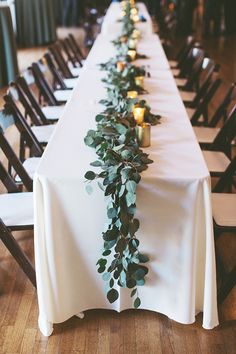 a long table with candles and greenery on it