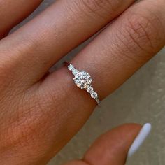 a woman's hand with a diamond ring on top of her finger and an engagement band in the middle