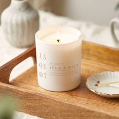 a white candle sitting on top of a wooden tray